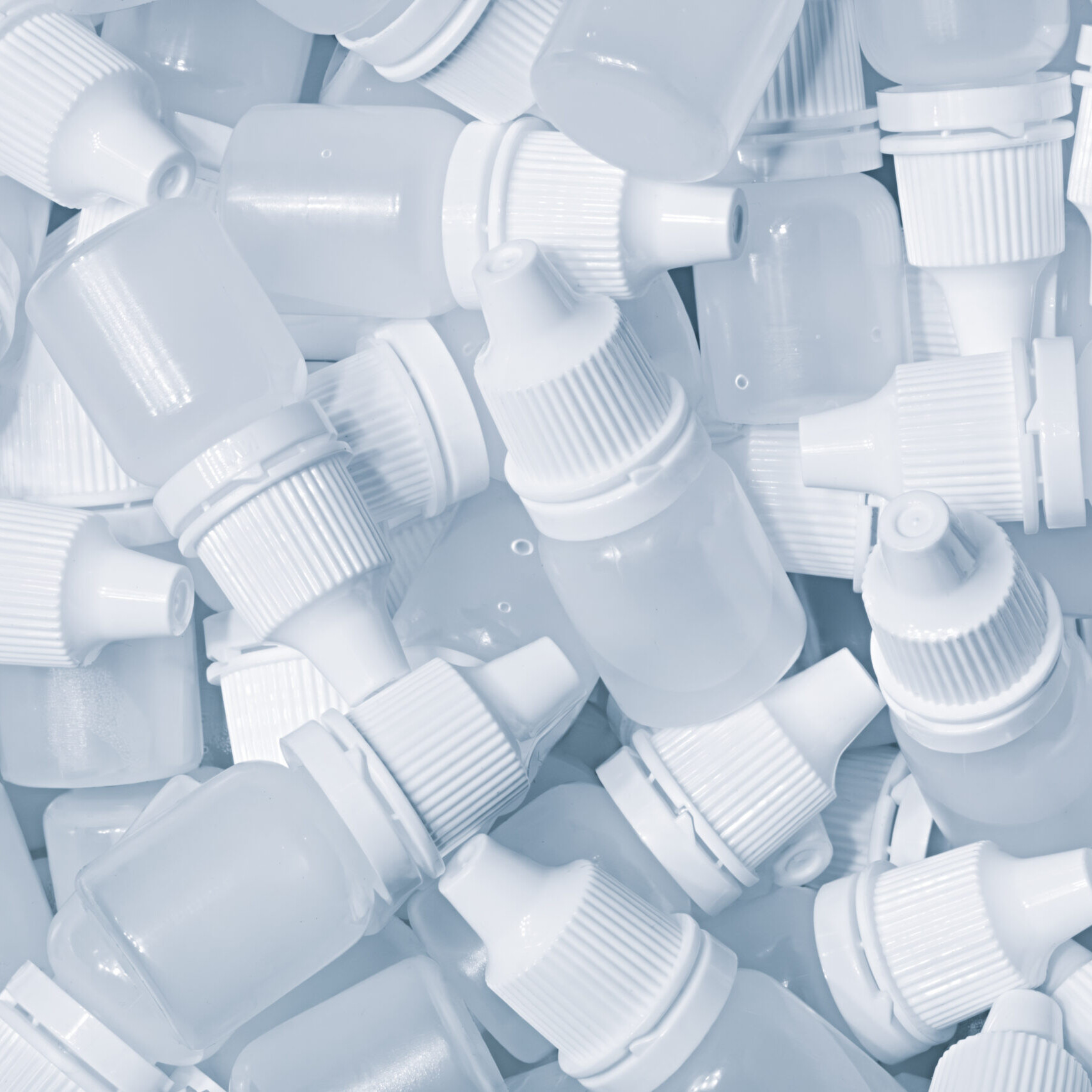 White plastic medical bottles vials for medicinal nose or eye drops as a solid white textured background, medical health concept